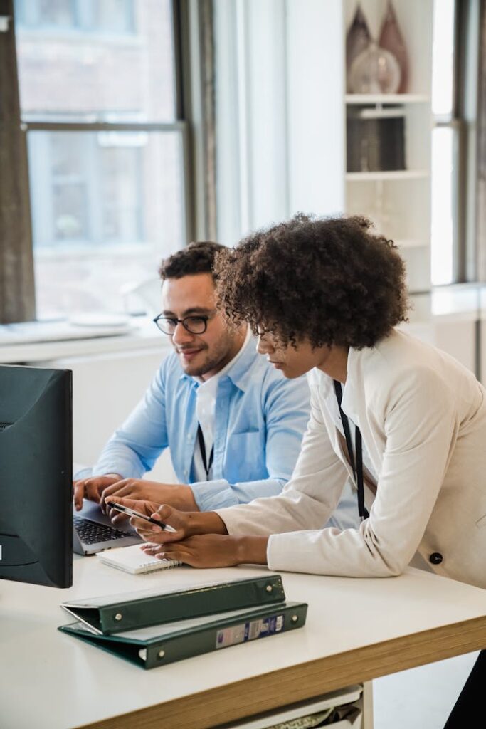 Two professionals collaborating at a desk in a modern office with natural light.